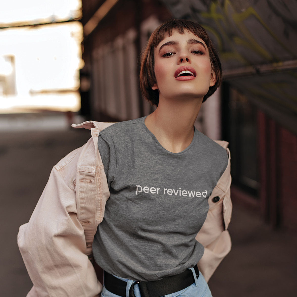 Woman wearing a gray 'peer reviewed' t-shirt outdoors
